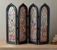 three stained glass windows sitting on top of a wooden table