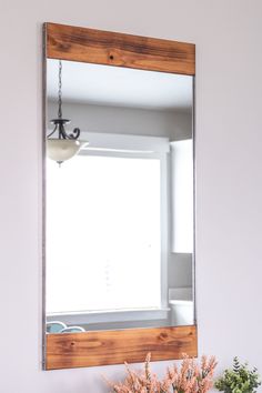 a mirror sitting on top of a wooden shelf next to a vase filled with flowers