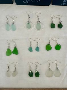 a collection of green and white sea glass dangles are displayed on a table