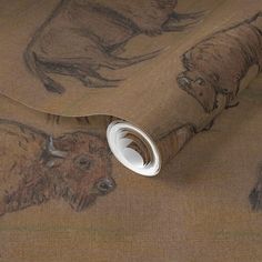 an animal themed wallpaper with bisons and buffalo on brown paper, next to a roll of tape