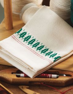 two white towels sitting on top of a wooden table next to knitting needles and yarn