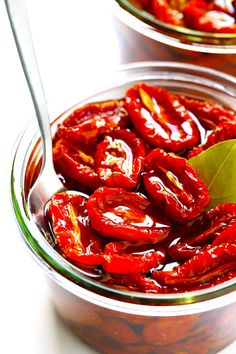 a bowl filled with red peppers and a green leaf on top of the other bowl