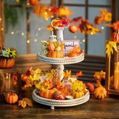 two tiered trays filled with different types of food and autumn decorations on top of a wooden table