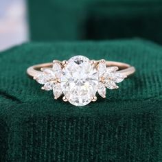 an engagement ring with three stones in the center on top of a green velvet box