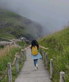 a woman walking down a path with her back to the camera and arms spread out