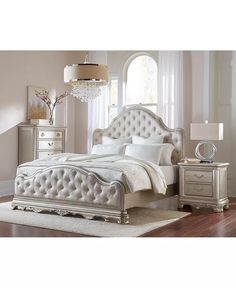 a white bed sitting in a bedroom next to a dresser and lamp on top of a hard wood floor