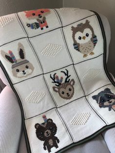 a crocheted blanket with animals and deers on it, hanging from the back of a chair