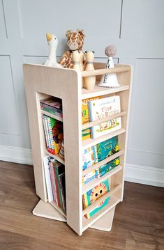 a wooden book shelf with books and stuffed animals on the top, in front of a white wall