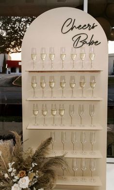 there is a wine glass rack with many glasses on it and flowers in the vase