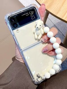 a person holding a cell phone case with white balls on it