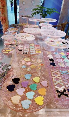 a table topped with lots of plates covered in confetti and heart shaped cookies