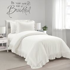 a white bed in a bedroom with a wall decal above it that says be your own kind of beautiful