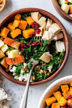 two bowls filled with different types of food on top of a white countertop next to silverware