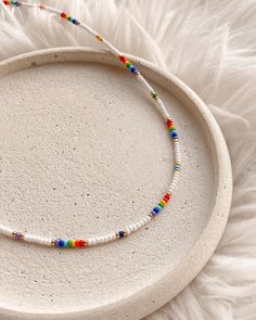 a white plate topped with a beaded necklace on top of a furnishing