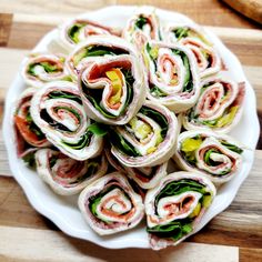 a white plate topped with cut in half sandwiches on top of a wooden cutting board