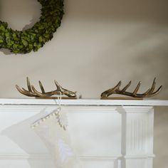 two deer antlers are on top of a mantle with a christmas stocking hanging from it