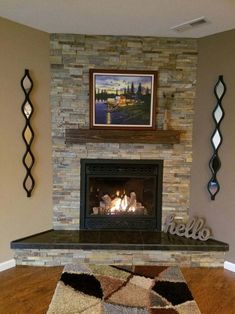 a living room with a fire place in the center and artwork on the wall above it