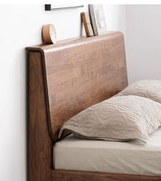 a bed with two pillows on top of it and a wooden headboard above the bed