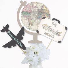 a vase filled with white flowers next to an airplane and the world awaits sign