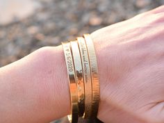 - Handmade rustic stacking cuff - Made from brass wire - shaped and textured by hand - Text or coordinates inside or outside the cuff - Textured or plain outside - Approximately 5mm wide - A minimal, elegant design - Looks great individually - or stacked together with other bracelet The most popular engravings: - You are loved. You are smart. You are beautiful. You are kind. You are important. - I love you to the moon and back - The greatest gift of life is friendship - Do not be afraid for I am Yellow Gold Name Bracelet With Engraving Option, Gold Hand Stamped Bracelets For Anniversary, Gold Hand Stamped Bangle Bracelets, Hand Stamped Gold Bracelets For Anniversary, Dainty Bracelet With Engraving Option For Gift, Gold Bracelets With Engraving Option For Anniversary, Adjustable Gold Bracelet With Engraving Option For Gift, Adjustable Gold Bangle With Engraving Option, Gold Bracelet With Engraving Option For Anniversary