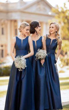 three women in blue dresses standing next to each other with bouquets on their laps