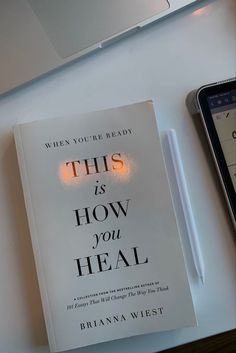 a book sitting on top of a desk next to a cell phone and laptop computer