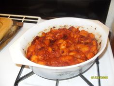 a white bowl filled with pasta and sauce on top of a stove