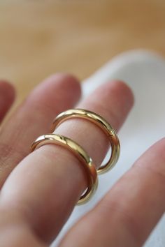 a person's hand with three gold rings on their fingers and one in the middle