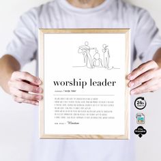 a man holding up a framed poster with the words worship leader in front of him