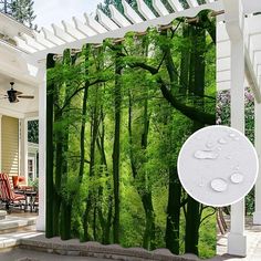 an outdoor shower curtain with green trees and water droplets on the ground in front of it