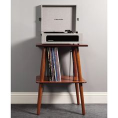 an old fashioned record player sitting on top of a wooden shelf next to a wall