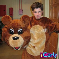 a man dressed as a teddy bear holding a bagel in one hand and wearing a costume on the other