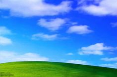 a green hill under a blue sky with clouds