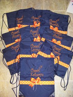 six blue bags with orange bows and name on them