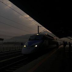 a white train traveling down train tracks next to a platform with people standing on it