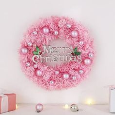 a pink wreath with merry christmas written on it