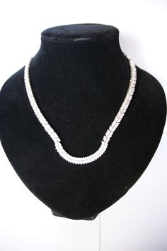 This is a fabulous Silver and Cubic Zirconia necklace. The design is absolutely stunning with alternate sections of six and four leaves encrusted with bright Cubic Zirconia stones. Each section is securely attached to the next and moves with a snake like fashion. The front section has a 'U' shape, this is rigid so holds its shape permanently. The necklace has been beautifully crafted. The catch has a safe and secure push-in catch. The necklace measures 43cm long and 0.6cm wide. It is stamped 925 Classic Cubic Zirconia Necklaces With Bling, Classic Cubic Zirconia Necklace With Bling, Classic Diamond Necklace With Bling, Cubic Zirconia Costume Jewelry Necklace, Elegant Cubic Zirconia Tennis Necklace With Bling, Elegant Cubic Zirconia Diamond Necklace With Bling, Formal Costume Jewelry Necklaces With Cubic Zirconia, Elegant Silver Tennis Necklace With Bling, Formal Fine Jewelry Necklaces With Bling