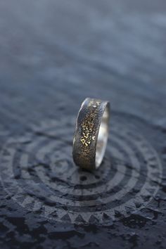 a close up of a wedding ring on the ground with water in the foreground