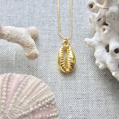 We love this fun and summery, beachy necklace. Answer the siren's song and get one for yourself or someone you love. Would make a great gift for the surfer or beach-lover in your life! A 14k gold electroplated cowrie shell dangles from a lustrous, high quality gold filled snake chain. The perfect summertime accessory! Chain: Gold fill, length 16" Cowrie Pendant: 22k Gold plated size: 26 x 18 mm✦ JEWELRY CARE ✦✧ Warm water and a soft cloth are the best thing you can do to maintain the beauty of y Gold Shell Necklace With Starfish Charm For Summer, Gold Shell Necklace With Starfish Charm As Gift, Handmade Gold Shell Strand, Handmade Gold Strand Shell, Beachy Gold Shell Necklace As A Gift, Beachy Gold Shell Necklace For Gifts, Beachy Gold Shell Necklace For Gift, Beachy Gold Shell Necklace Perfect For Gifts, Gold Shell Necklace With Starfish Charm For Vacation