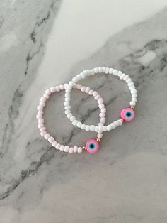 This pink evil eye bracelet is designed to bring anyone who wears it positive energy & protection. Available with either white or light pink 4mm glass beads Materials Used: White/Light Pink Beads: Glass Gold Beads: 14K gold plated Eye: Polymer Clay Stretch bracelet: Made to order in your wrist size Customization available: If you would like to adjust something in the design feel free to message me and I will do my best to accommodate! Spiritual Pink Hand-strung Stretch Bracelet, White Friendship Bracelets With Evil Eye, White Evil Eye Friendship Bracelets, Pink Round Spiritual Beaded Bracelets, Spiritual Pink Round Stretch Bracelet, Adjustable Pink Evil Eye Bracelet, Pink Beaded Evil Eye Bracelet With Round Beads, Pink Spiritual Stretch Bracelet With Round Beads, Spiritual Pink Stretch Bracelet With Round Beads