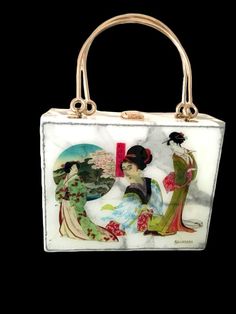 A very unusual handbag in a box shape with two gold top handles that features Japanese Geisha Artwork.  The print is created by the Designer as a pastiche of separate Ukiyo-e masterpieces. This artwork takes the centre stage on the bag at its front. The rest of the bag features a marble look grey/white subtle pattern in faux leather. The back of this luxury handbag has a textured 3D pattern in clear and metallic blue colours.  The inside of the bag is beautifully finished in fabric lining.  Stan Rectangular Shoulder Bag With Top Carry Handle As Gift, Rectangular Shoulder Bag With Top Carry Handle, Square Evening Bag, Rectangular Box Bag As Gift, White Rectangular Case Bag For Gifts, White Rectangular Case Bag As A Gift, Square Box Bag With Top Carry Handle For Gift, Square Box Bag With Top Carry Handle As Gift, Top Handle Box Bag With Detachable Handle