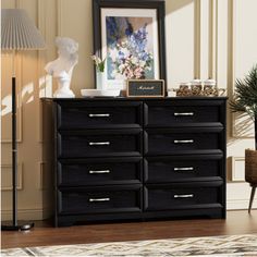 a black dresser sitting in a living room next to a lamp