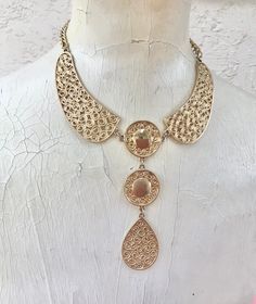 Lot of 2 super cool vintage mid-century gold tone necklaces, sold together only. First one is a fun collar necklace with an ornate circular geometric design. Original necklace was super short, so an extender has been added for adjustability. Hook closure, you can hook to where you like it. Approximately 18.25 inches maximum length. Second necklace has a vintage teardrop shaped medallion. Original clasp was degraded and replaced with a large lobster claw. Adjustable also. 24 inches length, pendan Ornate Metal Choker Necklace, Vintage Brass Choker Necklace, Retro Gold Adjustable Choker, Retro Adjustable Gold Necklace, Adjustable Retro Gold Necklace, Vintage Brass Medallion Necklace, Ornate Gold-tone Metal Jewelry, Elegant Metal Medallion Necklace, Vintage Metal Bib Necklace For Gift