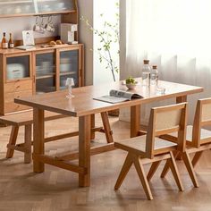 a wooden table and chairs in a room with white walls, wood flooring and open shelves