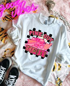 a white t - shirt with pink lettering on it next to some black and yellow shoes