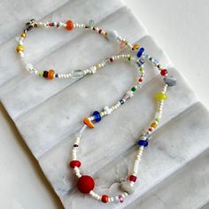 a multicolored beaded necklace is displayed on a white marble slabd surface