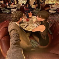 two people sitting at a table with plates of food