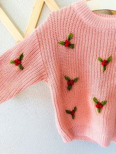 a pink sweater with holly decorations on it