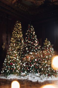 three christmas trees are decorated with white and red flowers in the middle of a room