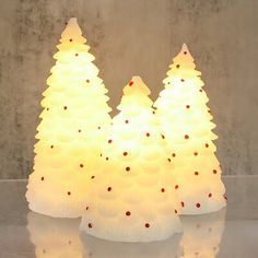 three small white christmas trees sitting on top of a table